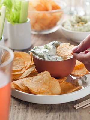 Platter of potato chips and fresh vegetables with dip.