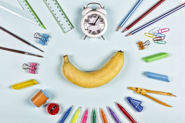 Back to school items laid out flat in a ring around a banana.